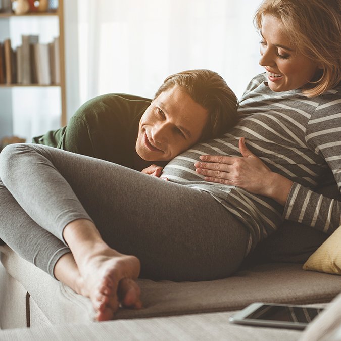 Glad future father hearing abdomen of pregnant woman Echo met beeld